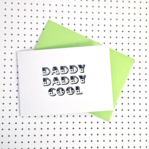 wenskaart met de tekst daddy cool. Zwarte circusletters op een witte achtergrond, met een groene envelop